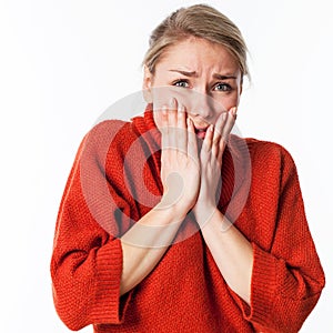 Nervous young blond woman hiding her face for worry and fear