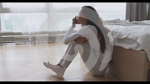 Nervous young mixed race girl sitting on floor in bedroom.