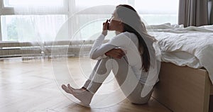 Nervous young mixed race girl sitting on floor in bedroom.