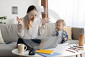 Nervous young mother of toddler working from home, suffering troubles with laptop at home, emotionally reacting to news