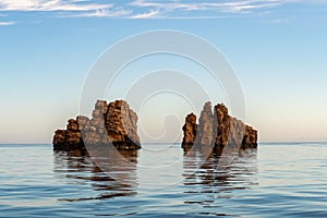 Nes Portes Rocks with a cross on top, north of Paros Island sticking out from perfectly flat calm Mediterranean Sea, Greece