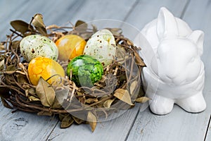 Nest with colored Easter eggs and ceramic rabbit box