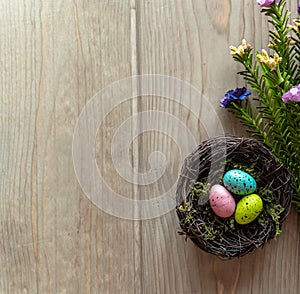 Nest with colorful eggs on aged wood