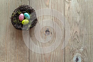 Nest with colorful eggs on aged wood