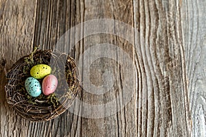 Nest with colorful eggs on aged wood