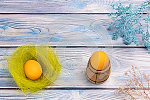 Nest with Easter egg and a small barrel on the wooden background