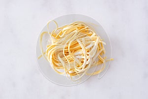 Fresh linguine pasta, top view against white marble photo