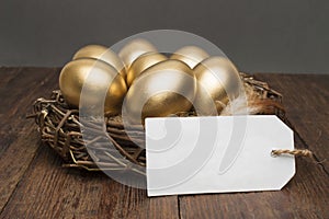 Nest with golden eggs with a tag and place for text on a wooden background. The concept of successful retirement