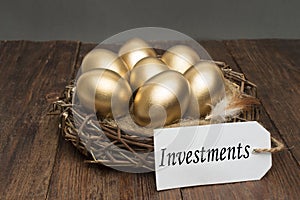 Nest with golden eggs with a tag and a word of investments on a wooden background. The concept of successful retirement