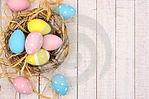 Nest side border with pink, yellow & blue Easter Eggs against white wood