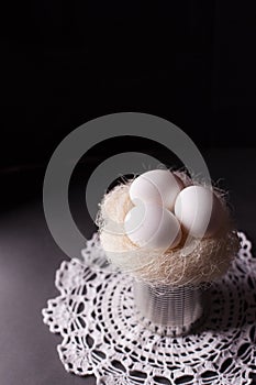 Nest with white eggs on a dark background - rustic composition, purity and minimalism.