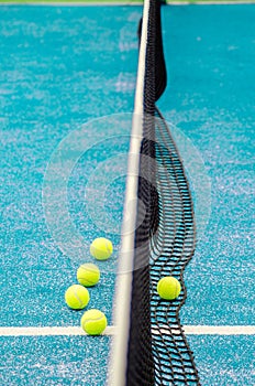 net of a blue paddle tennis court and five balls