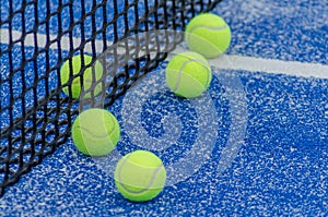 net of a blue paddle tennis court and five balls