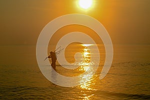 Net Fisherman ocean wading with tropical sunrise seascape , Thailand