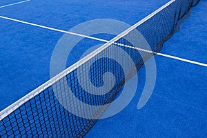 Net an lines on a blue paddle tennis court, synthetic grass