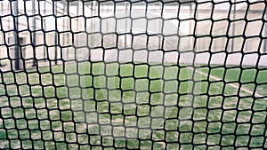 Net and part of green synthetic grass paddle tennis court indoor without people