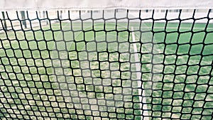 Net and part of green synthetic grass paddle tennis court indoor without people