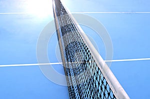 Net of tennis court with white border line on blue floor