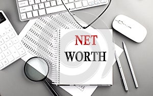 NET WORTH text on notepad on chart with keyboard and calculator on grey background
