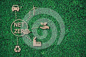 Net zero text with earth between energy saving icon paper cut on green grass background with copy space , green energy iconic