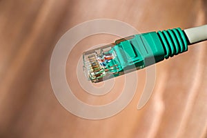 Network cable connector RJ45 close up view. LAN head cable macro view with wooden background.