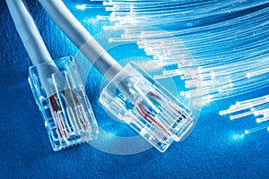 Network cables and bundle of optical fibers with lights in the ends. Blue background