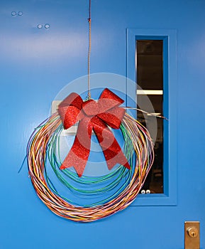 Network Cabling Christmas wreath with glittery bow hung on blue door