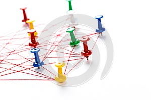 Network with colorful pins and string,  linked together with string on a white background suggesting a network of connections