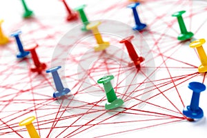 Network with colorful pins and string,  linked together with string on a white background suggesting a network of connections