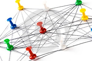 Network with colorful pins and string,  linked together with string on a white background suggesting a network of connections