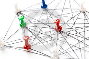 Network with colorful pins and string,  linked together with string on a white background suggesting a network of connections