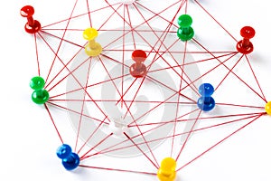 Network with colorful pins and string,  linked together with string on a white background suggesting a network of connections