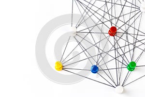 Network with colorful pins and string,  linked together with string on a white background suggesting a network of connections