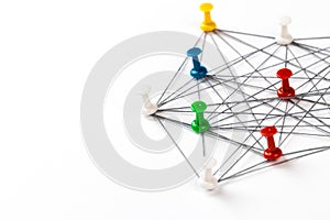 Network with colorful pins and string,  linked together with string on a white background suggesting a network of connections