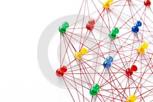 Network with colorful pins and string,  linked together with string on a white background suggesting a network of connections