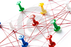 Network with colorful pins and string,  linked together with string on a white background suggesting a network of connections