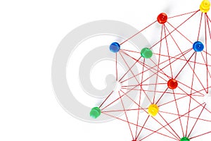 Network with colorful pins and string,  linked together with string on a white background suggesting a network of connections