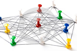 Network with colorful pins and string,  linked together with string on a white background suggesting a network of connections