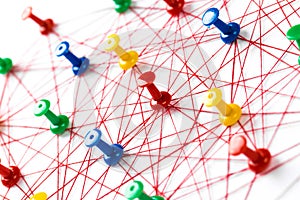 Network with colorful pins and string,  linked together with string on a white background suggesting a network of connections
