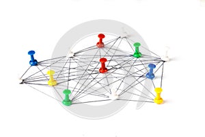 Network with colorful pins and string,  linked together with string on a white background suggesting a network of connections