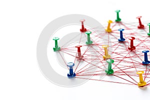 Network with colorful pins and string,  linked together with string on a white background suggesting a network of connections