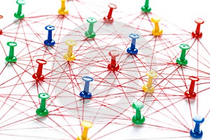 Network with colorful pins and string,  linked together with string on a white background suggesting a network of connections