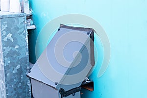 Network electric cable with metal flex large gray metal box clings to a blue wall.