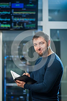 Network engineer in server room with pen and tablet