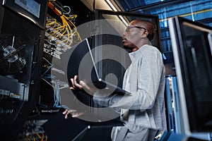 Network Engineer using Laptop in Server Room