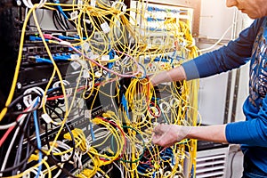 Network engineer working in server room. Connecting network cables to switches