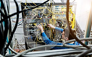 Network engineer working in server room. Connecting network cables to switches