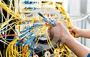 Network engineer working in server room. Connecting network cables to switches