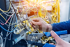 Network engineer working in server room. Connecting network cables to switches