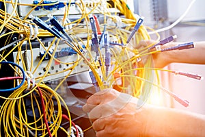 Network engineer working in server room. Connecting network cables to switches